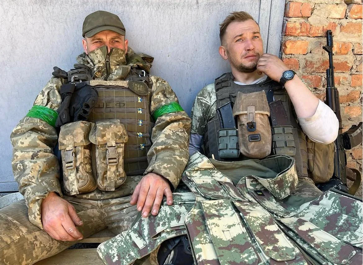 Two Ukrainian soldiers seated in combat gear during field coverage in Ukraine